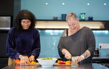 Zwei Frauen kochen gemeinsam und schneiden Gemüse.