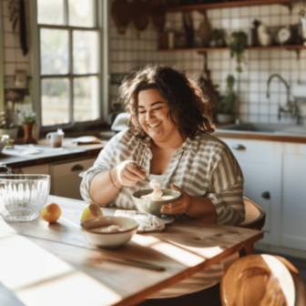 Eine plus size rau sitzt ein ihrer Küche und isst eine Joghurt Bowl.