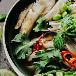 Asiatische Ramen Bowl mit Reisnudeln, Pilzen, Koriander und Gemüse.