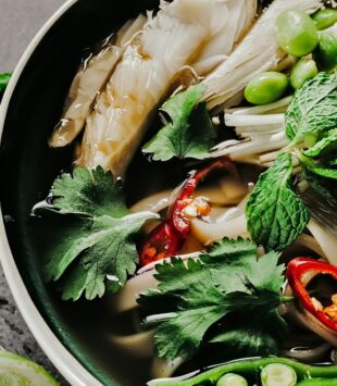 Asiatische Ramen Bowl mit Reisnudeln, Pilzen, Koriander und Gemüse.