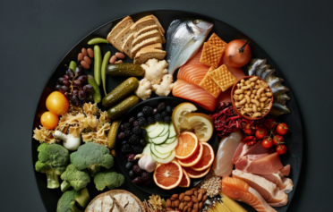 Eine Platte mit Gemüse, Kohlenhydrate, Proteinen, gesunden Fetten, Fisch und Fleisch als Makronährstoffe.
