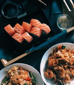 Ein Tisch mit Sushi Rollen sowie Nudeln Gerichte