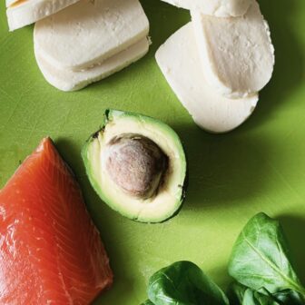 Avocado, Lachs und Mozarella liegen auf einer grünen Oberfläche
