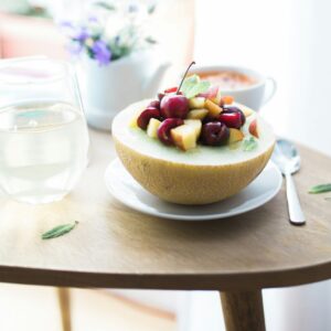 Eine Honigmelone gefüllt mit frischen Beeren auf einem Teller.