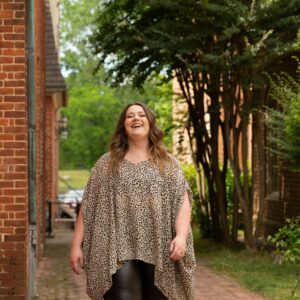 Eine plus size Frau geht spazieren und schaut glücklich in die Kamera.