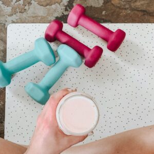 Eine Sportmatte mit Hanteln und einem Glas mit einem Shake.