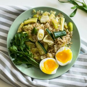 Reis mit Gemüse und gekochtem Ei auf einem grünen Teller