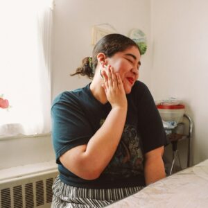 Eine junge lächelnde plus size Frau sitzt an einem Tisch.