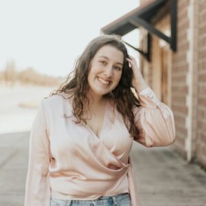 Junge lachende Frau in einer rosa Bluse.