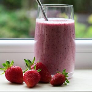 Ein Glas mit einem roten Beerensmoothie.