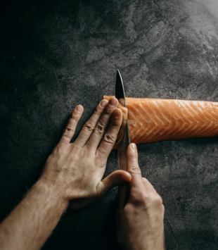 Hände von einem Mann schneiden ein frisches Lachs Fillet