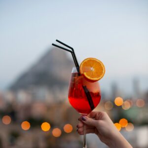 Eine Aufnahme von einem Glas Aperol Spritz mit einer Orangenscheibe und einem Strohhalm darin.