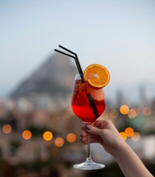 Eine Aufnahme von einem Glas Aperol Spritz mit einer Orangenscheibe und einem Strohhalm darin.