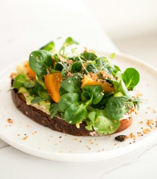 Ein frisches Brot belegt mit Avocado und Feldsalat.