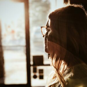 Eine junge Frau sieht nachdenklich aus dem Fenster.