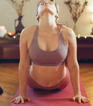 Eine junge Frau macht eine Yoga Übung auf einer Yoga Matte.