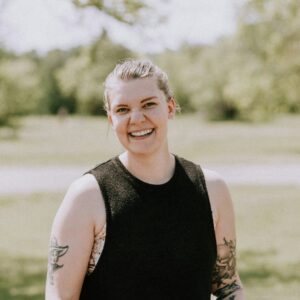 Eine junge selbstbewusste Frau lacht fröhlich in die Kamera.