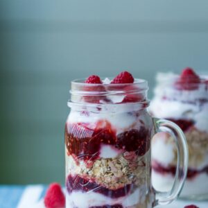 Ein Glas mit Schichtjoghurt mit Haferflocken und Erdbeeren.