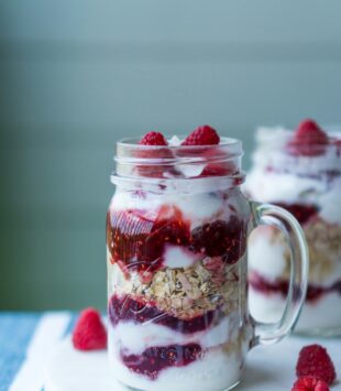 Ein Glas mit Schichtjoghurt mit Haferflocken und Erdbeeren.