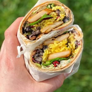 Eine Hand hält zwei Hälften von einem gesunden Wrap in die Kamera.