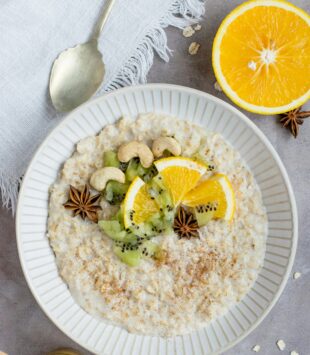 Eine Schale mit Porridge, getopped mit Orange, Kiwi und Cashews.