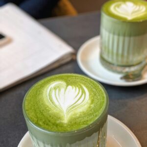 Zwei Gläser Matcha Latte auf einem Tisch im Cafe.