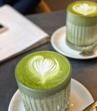 Zwei Gläser Matcha Latte auf einem Tisch im Cafe.