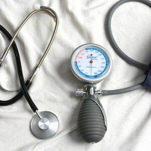 Ein Stetoskop und ein Gerät mit dem der Blutdruck gemessen werden kann, liegen auf einem weißen Laken.