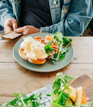 Ein Brot mit Lachs und Spiegelei mit Salatbeilage.