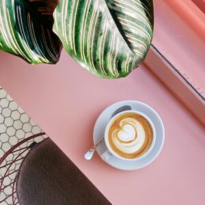 Eine Tasse Cappucino auf einem rosa Tisch im Cafe.