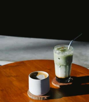 Eine Tasse Kaffee und ein Glas Matcha Latte auf einem Tisch.