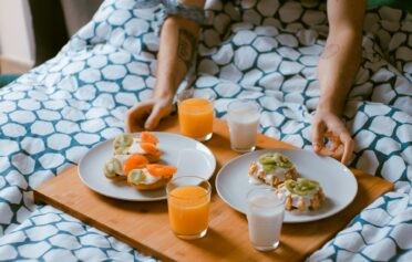 Ein Tablett mit Frühstück für zwei Personen im Bett.