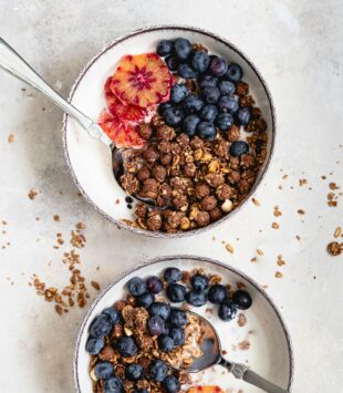 Zwei Joghurtbowls mit Granola und frischen Beeren.