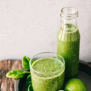 Ein Tablett mit einem Glas und einer Karaffe grünem frischen Saft.