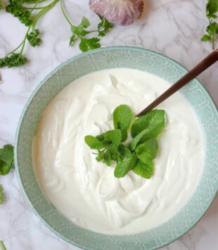Eine Schale mit frischem Quark, garniert mit einem frischen Minzblatt.