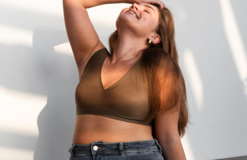 Eine junge curvy Frau fässt sich in die Haare und sitzt lässt auf dem Boden.