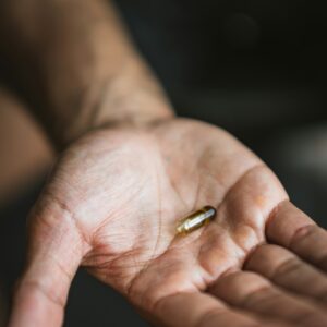 Eine Nahaufnahme einer Handfläche auf der eine Tablette in Kapselform liegt.