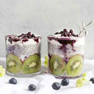 Zwei Gläser gefüllt mit Chiapudding, Kiwi und Beeren.