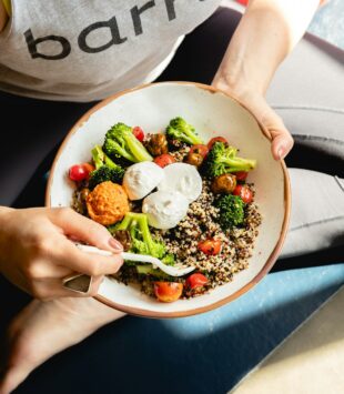 Eine Nahaufnahme einer gesunden veggie Bowl, die auf dem Schoß einer Person liegt.