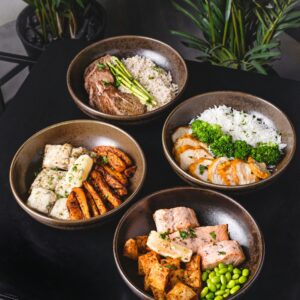 Vier Bowl mit verschiedenen gesunden Gerichten stehen auf einer Küchenplatte.