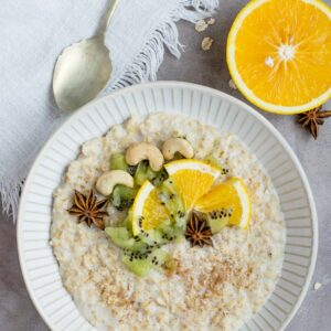 Eine Schale mit Porridge, garniert mit Obst und Cashews.