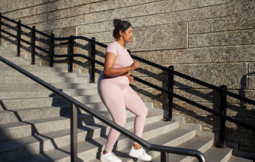 Eine Frau joggt einige Treppen in der Stadt hinunter.
