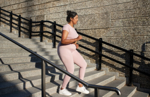 Eine Frau joggt einige Treppen in der Stadt hinunter.