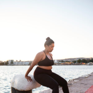 Eine kurvige Frau macht an einem Pfeiler am Hafen Sportübungen.