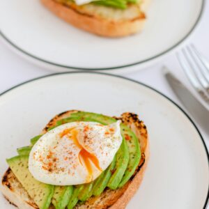 Ein Teller mit einer Scheibe Brot, die belegt ist mit Avocado und einem pochiertem Ei.