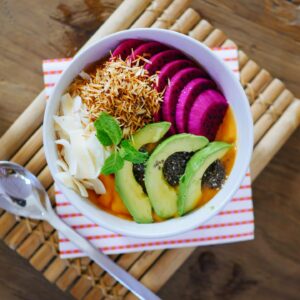 Eine bunte Frühstücksbowl mit Früchten und Avocado Slices.