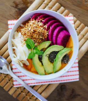 Eine bunte Frühstücksbowl mit Früchten und Avocado Slices.