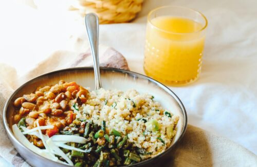 Ein Teller mit einer Gemüse-Quinoa-Salatbowl und einem Glas Orangensaft dazu.