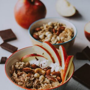 Eine Schale mit Musli, Joghurt und Apfelspalten.