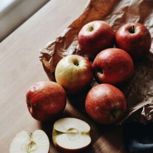 Auf einem Holzbrett liegen frische roe Äpfel, die zum Teil schon halbiert sind.